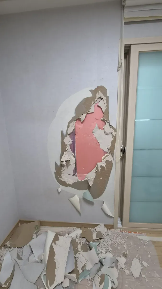 벽 깨짐 — 벽지를 걷어 내 드러난 손상 자리
